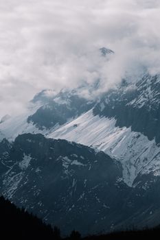 Scenic view of a snow-capped mountain range shrouded in clouds, capturing nature's majesty.