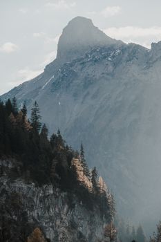 Stunning view of a mountain peak shrouded in mist with a forested foreground.