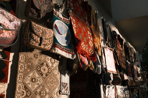 Free A vibrant array of traditional tapestries and bags hanging under warm lighting, creating a rich cultural scene. Stock Photo