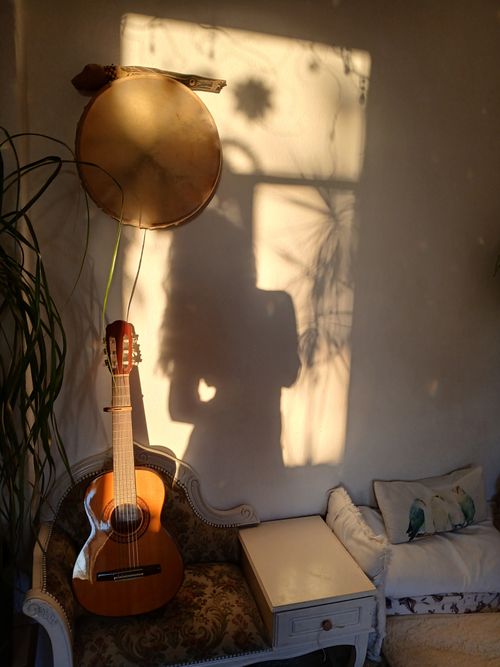 Free Warm boho living room featuring a guitar, drum, and plant shadows, creating a cozy atmosphere. Stock Photo