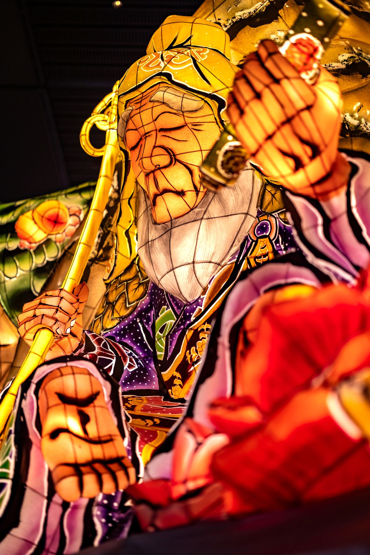 Close-up of an illuminated Nebuta float figure in vivid yellow, red, and blue — the artisan craftsmanship that defines Aomori's festival identity