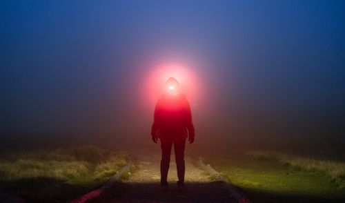 Free Person walking in foggy night with illuminated headlamp, creating a mysterious atmosphere. Stock Photo