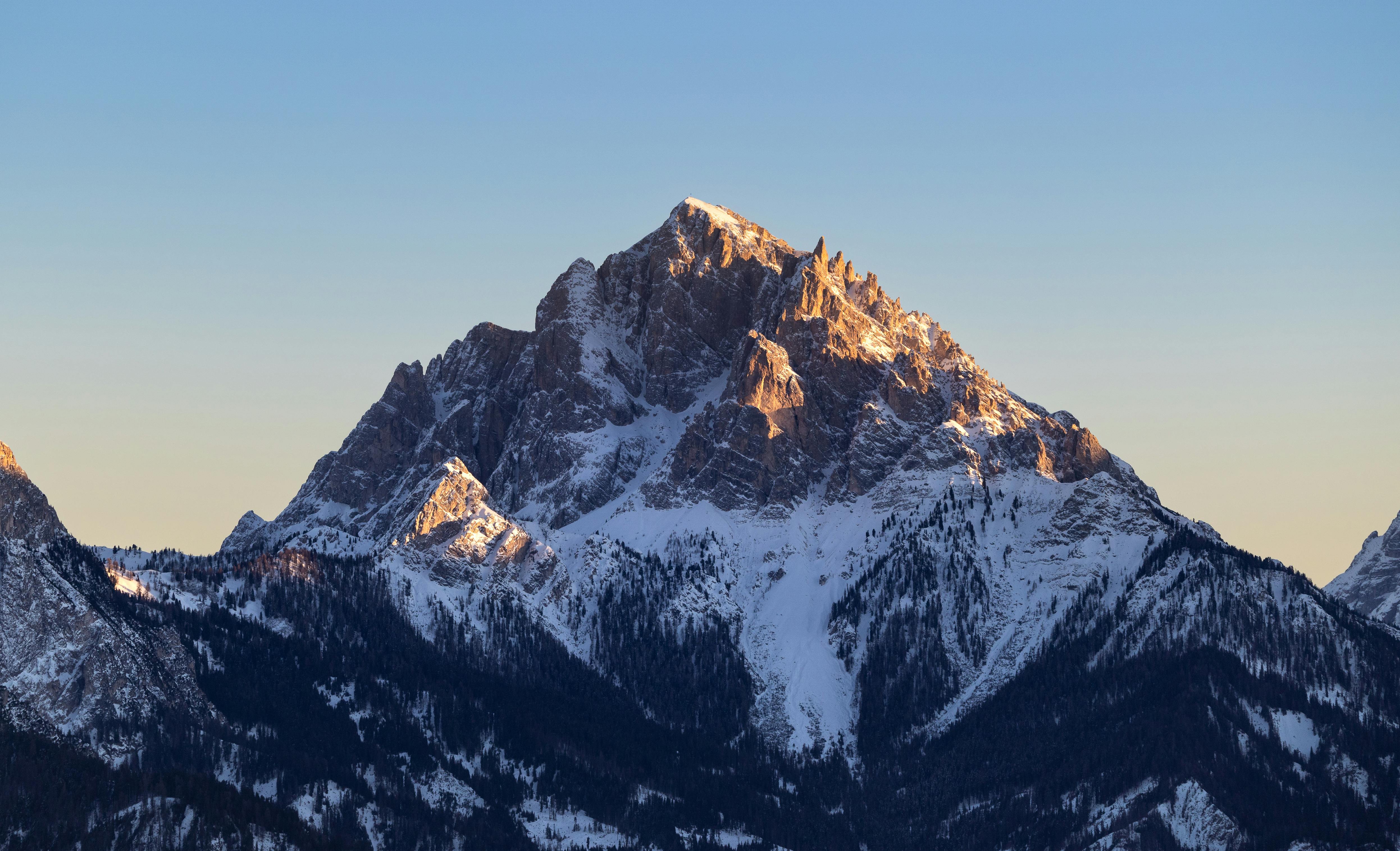 Experience the breathtaking beauty of a snow-covered mountain peak glowing under a vibrant sunset.