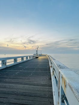 Tranquil pier with sunrise over calm ocean, perfect for peaceful escapes.