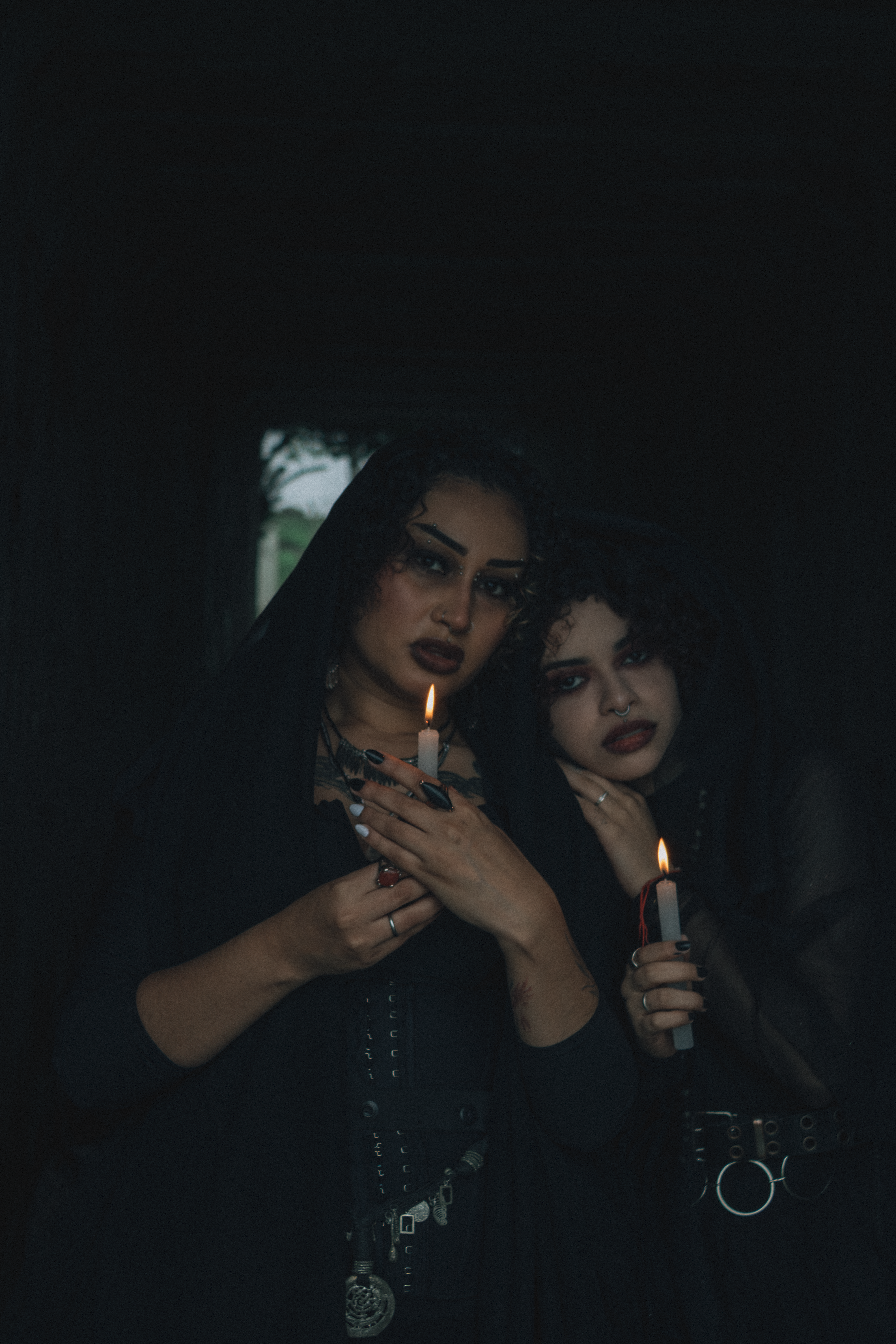 Two women with candles create a mysterious gothic ambiance.