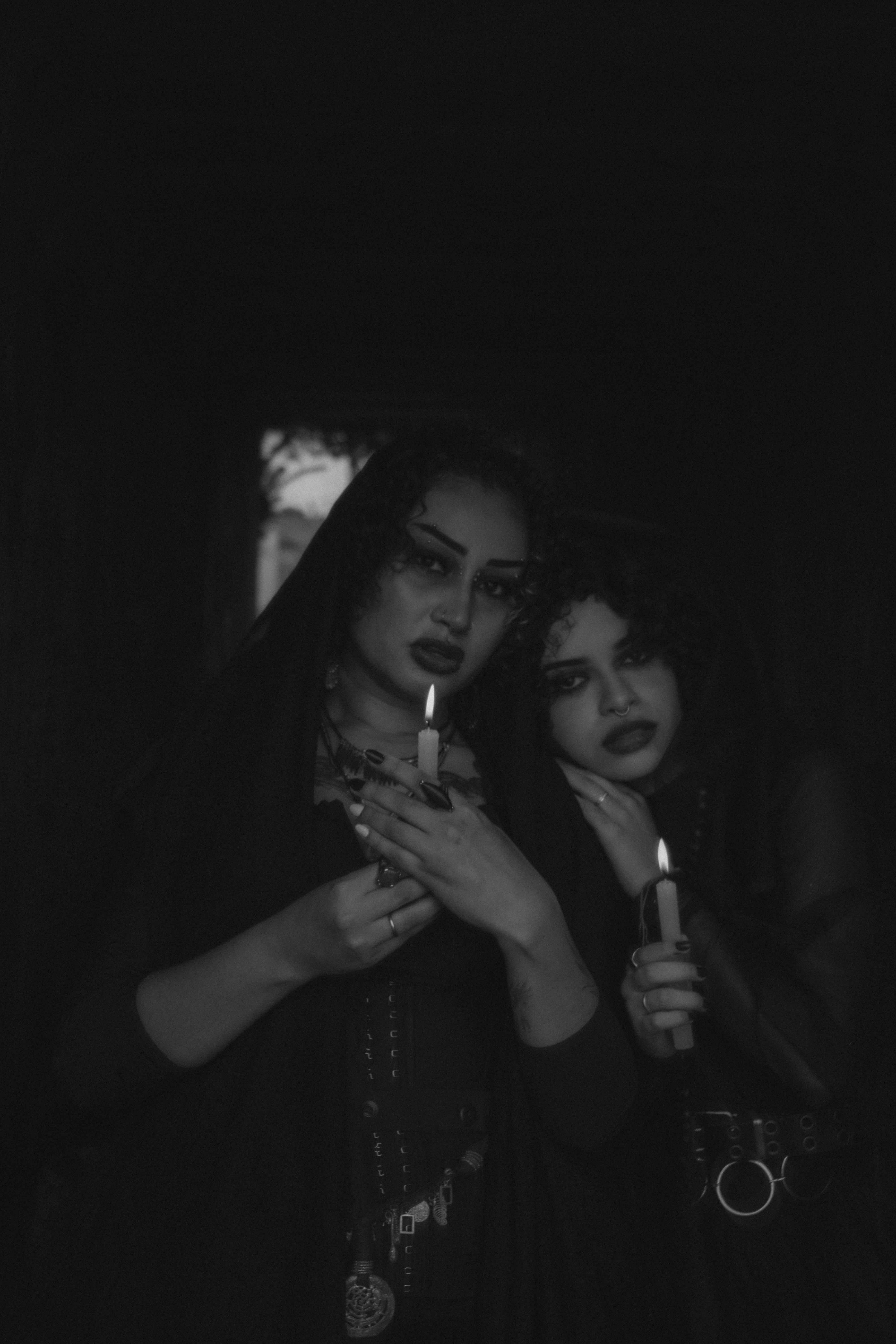 ingyenes Két gótikus ruhás nő gyertyákat tart a kezükben egy sötét, hangulatos környezetben, ami titokzatos hangulatot kelt. Stockfotó