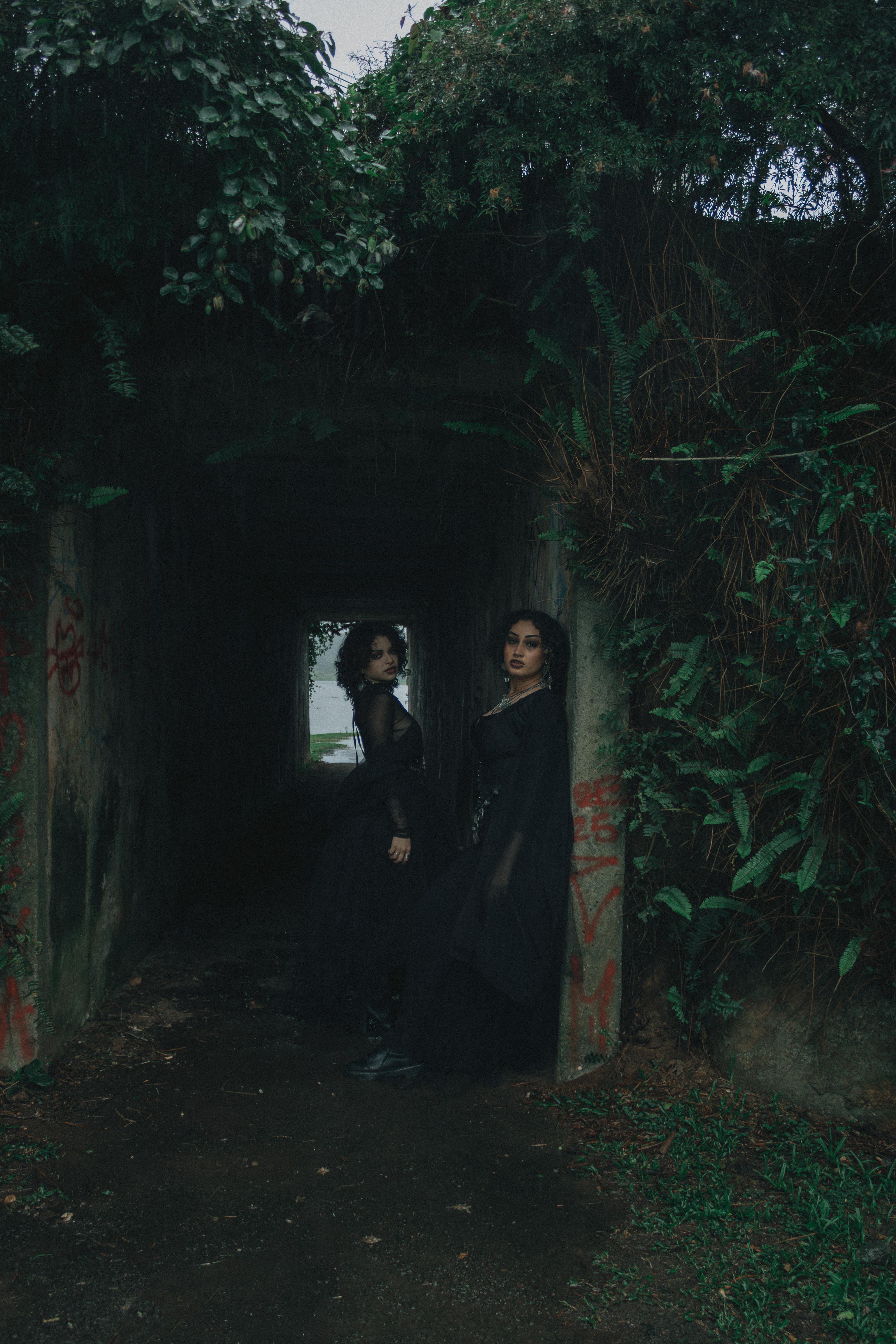 Zadarmo Dve ženy v tmavom gotickom oblečení pózujú v lesnom tuneli a vytvárajú tajomnú atmosféru. Fotka z fotobanky