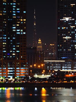 Captivating night cityscape of Dubai with Burj Khalifa amidst skyscrapers reflecting on water.