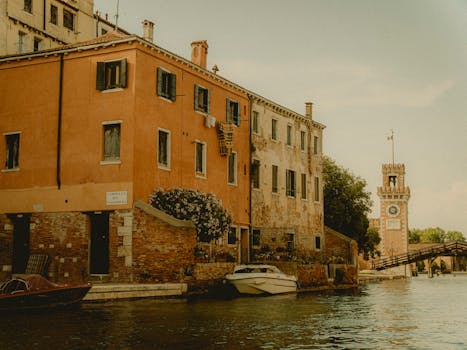 Charming Venetian canal with historic architecture and a glimpse of a clock tower on a summer day.