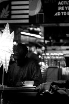 Black and white image of a cafe with a star lamp, coffee cup, and patrons deep in thought.