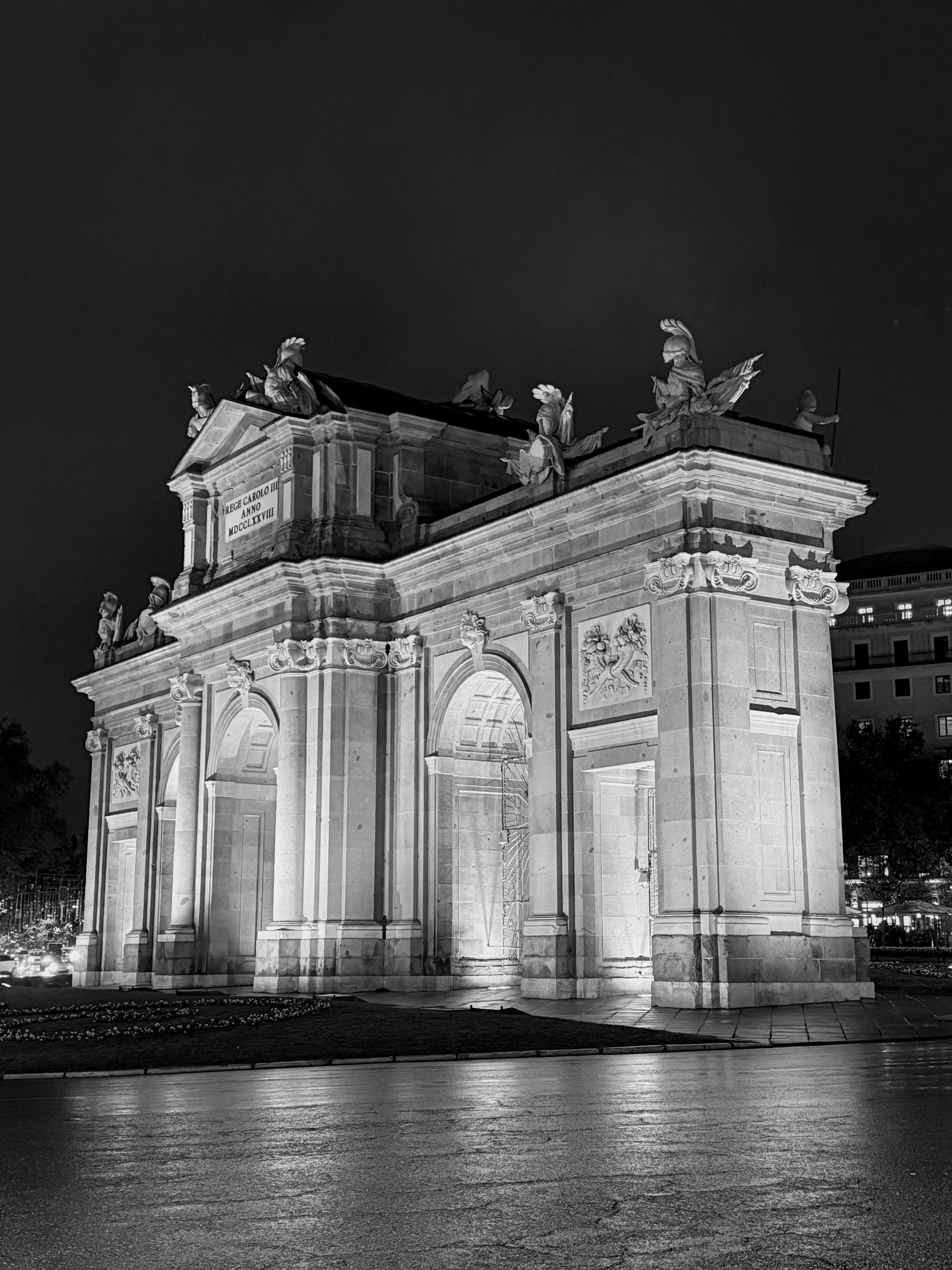 Elegant black and white capture of Puerta de Alcalá at night in Madrid, Spain.