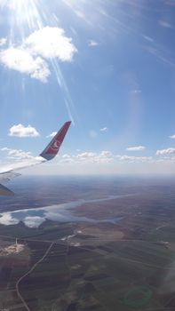 Aerial view of a Turkish landscape seen from an airplane, with sunlight and clouds enhancing the scenic beauty.