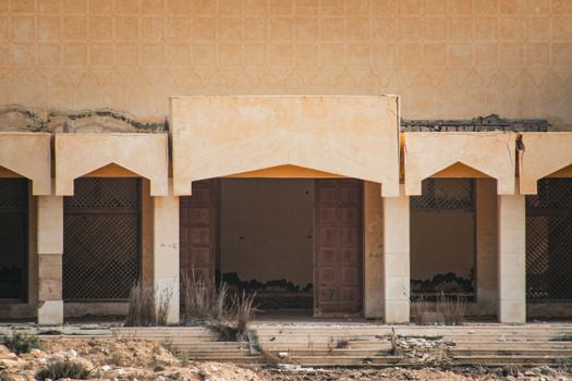 Weathered facade of an abandoned Middle Eastern building with traditional arches.