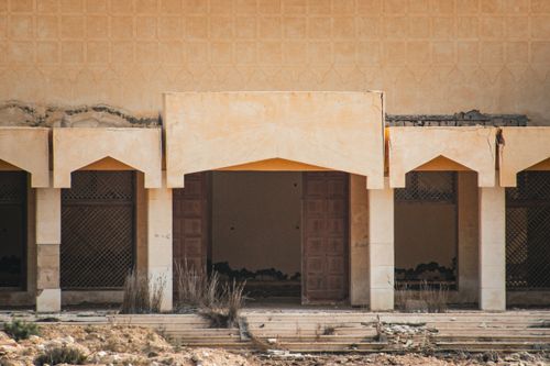Free Weathered facade of an abandoned Middle Eastern building with traditional arches. Stock Photo