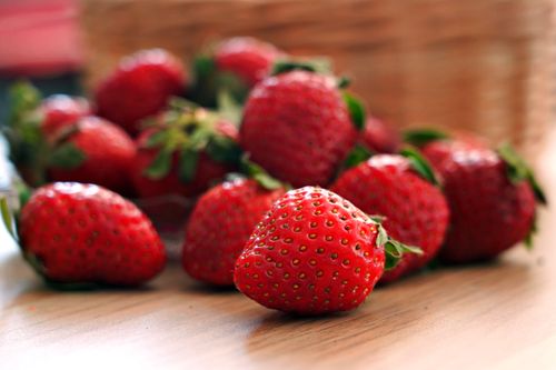 Free Vibrant red strawberries scattered on a wooden surface, perfect for health and food concepts. Stock Photo