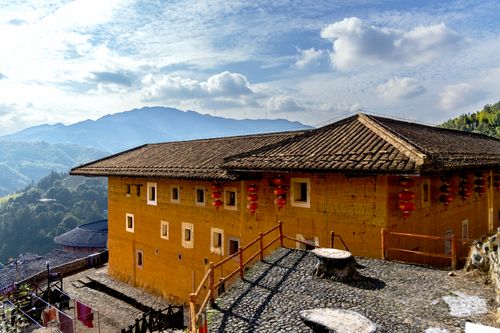 Free Scenic view of a traditional Fujian Tulou with mountains in the background under clear skies. Stock Photo