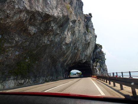 Experience a drive through a stunning Italian mountain tunnel, showcasing rugged rock formations.
