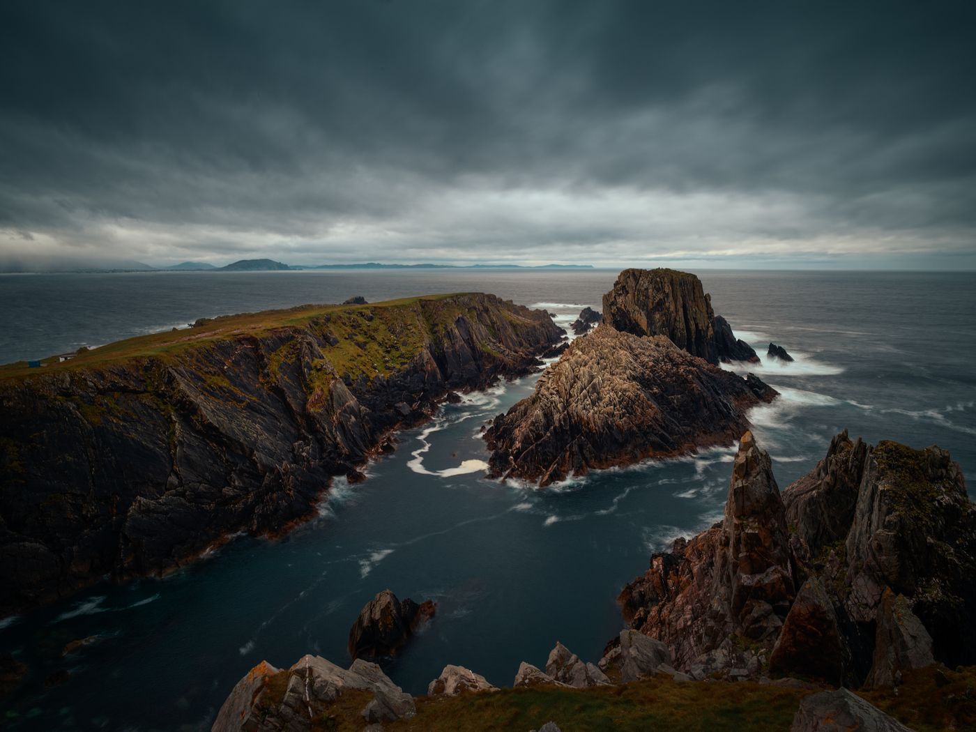A dramatic rocky coastline under a low, moody sky