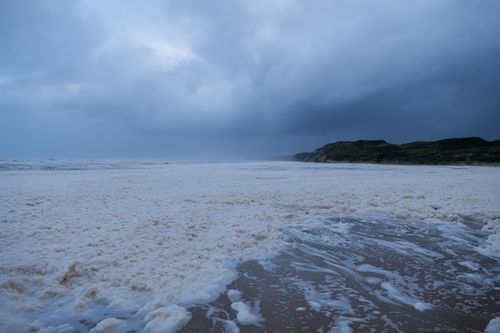 Free Captivating image of ocean foam on a sandy beach under a dramatic stormy sky. Stock Photo