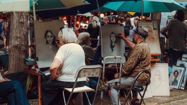 Street artists capture portraits in a lively outdoor market, showcasing artistic talent.