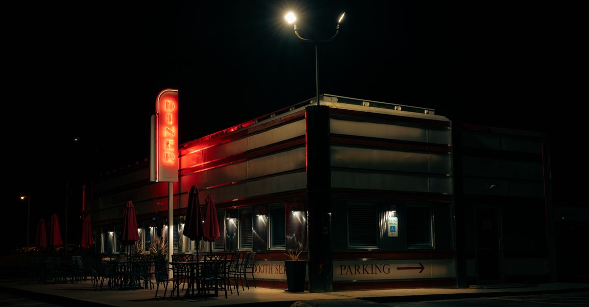 retro American diner at night with neon sign and people at the counter