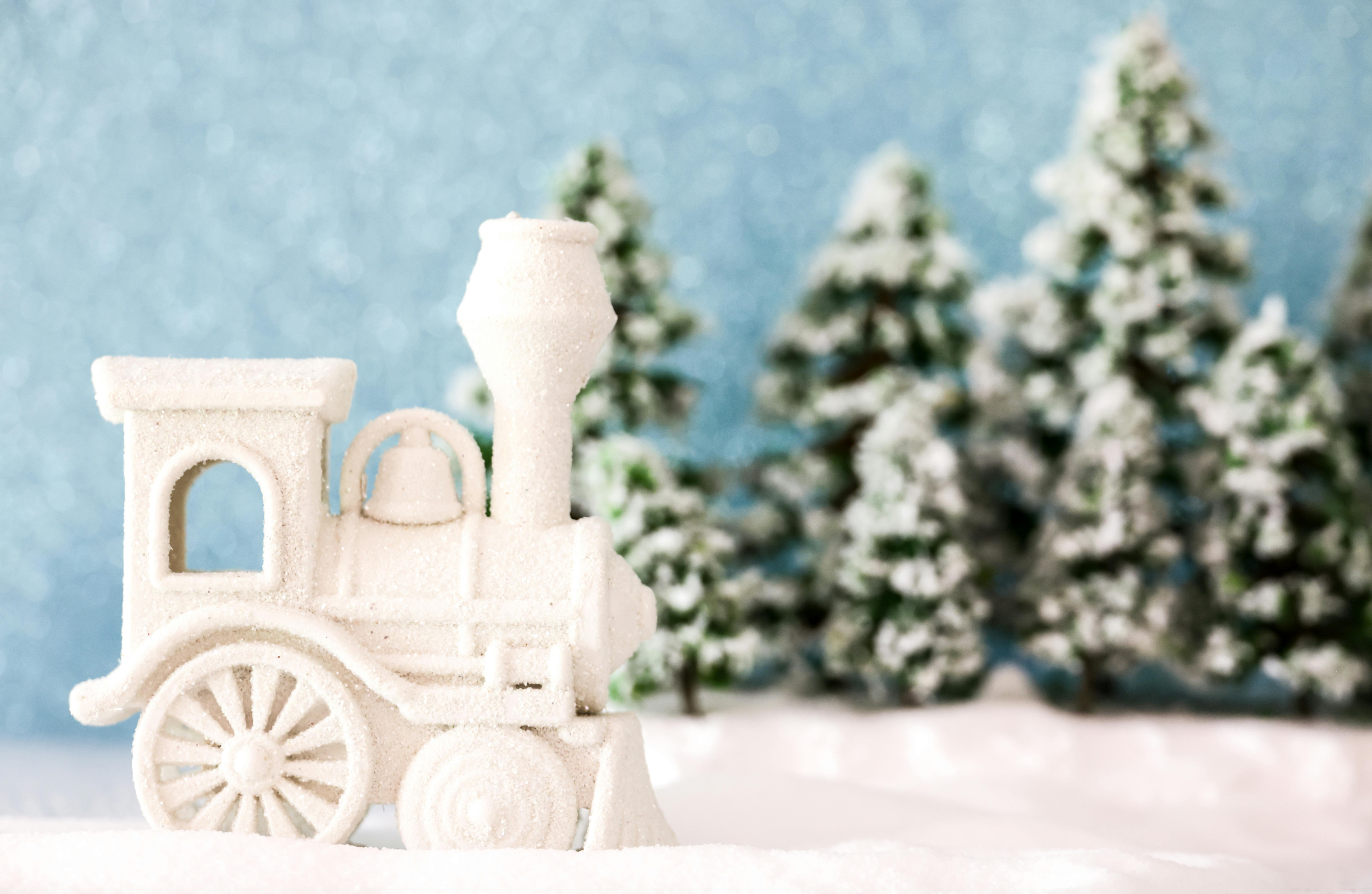 White toy train surrounded by snowy pine trees, creating a festive winter ambiance.