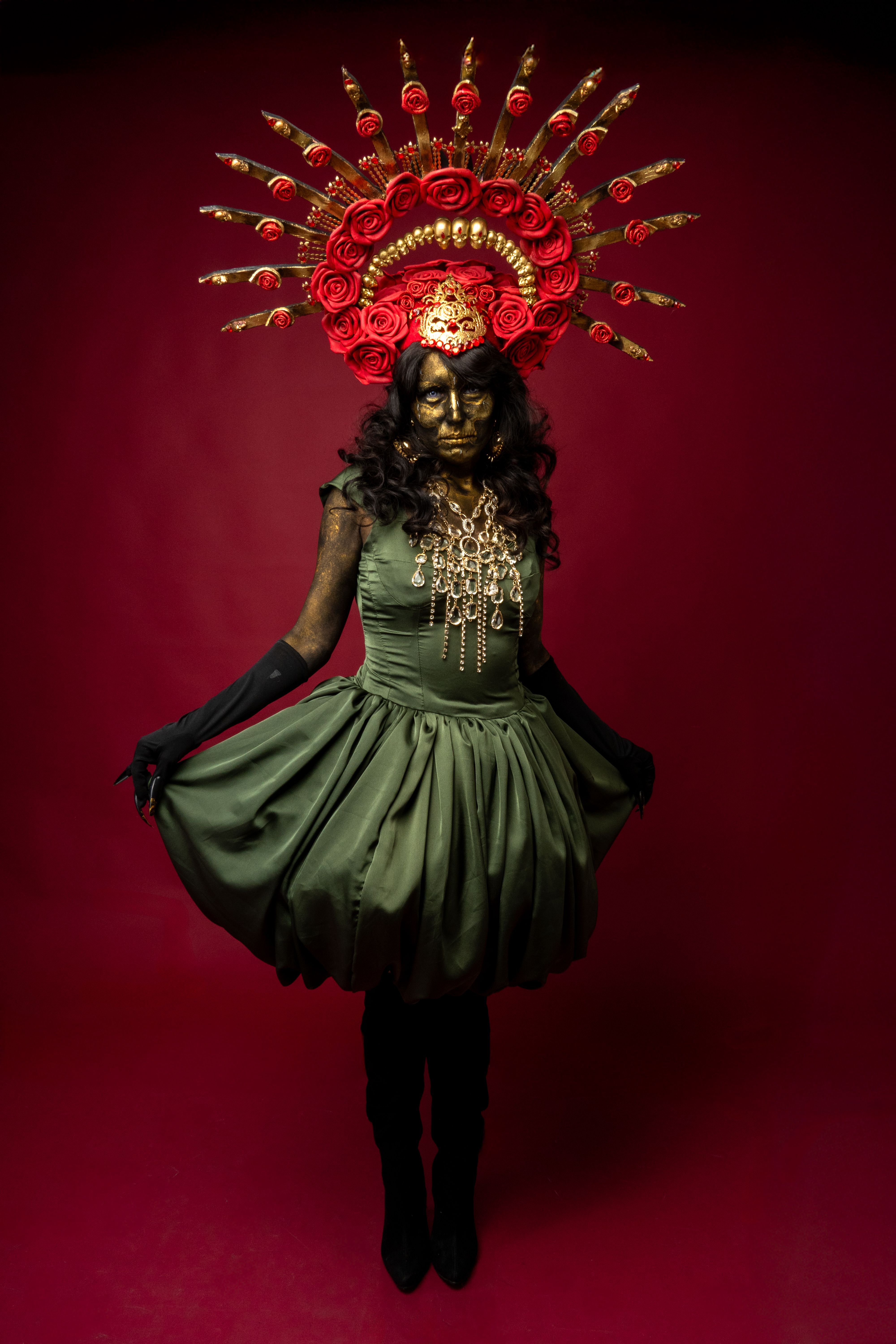 Beautiful Catrina model in traditional Mexican attire with flower headdress and gold makeup.