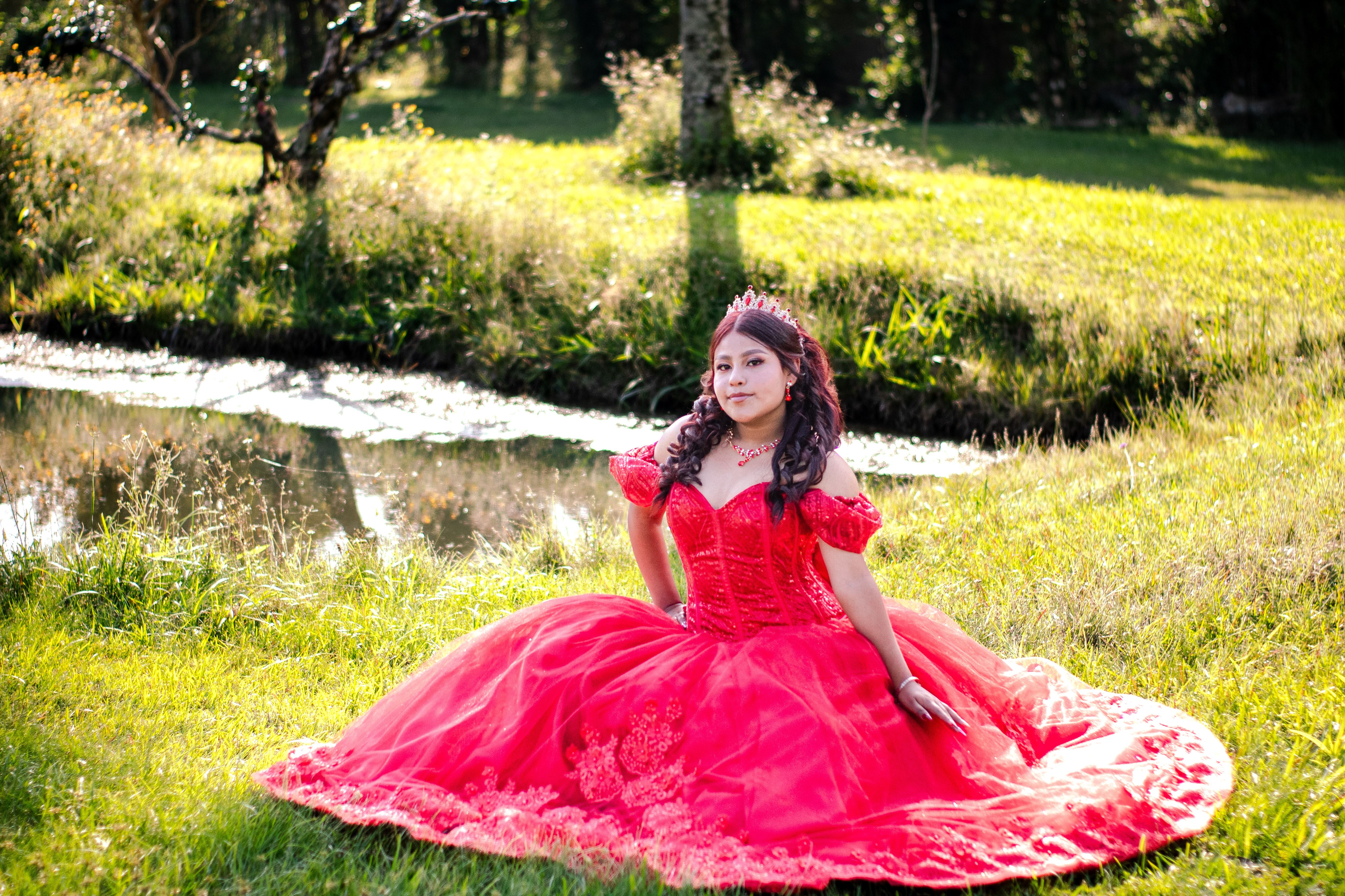 Elegant Woman in Red Dress Outdoors by a Stream · Free Stock Photo