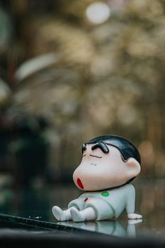 Charming figurine of a cartoon character resting on a reflective surface in an outdoor setting.