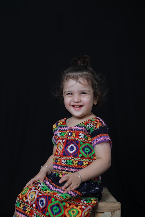 Free Adorable toddler smiling sitting indoors with colorful attire Stock Photo