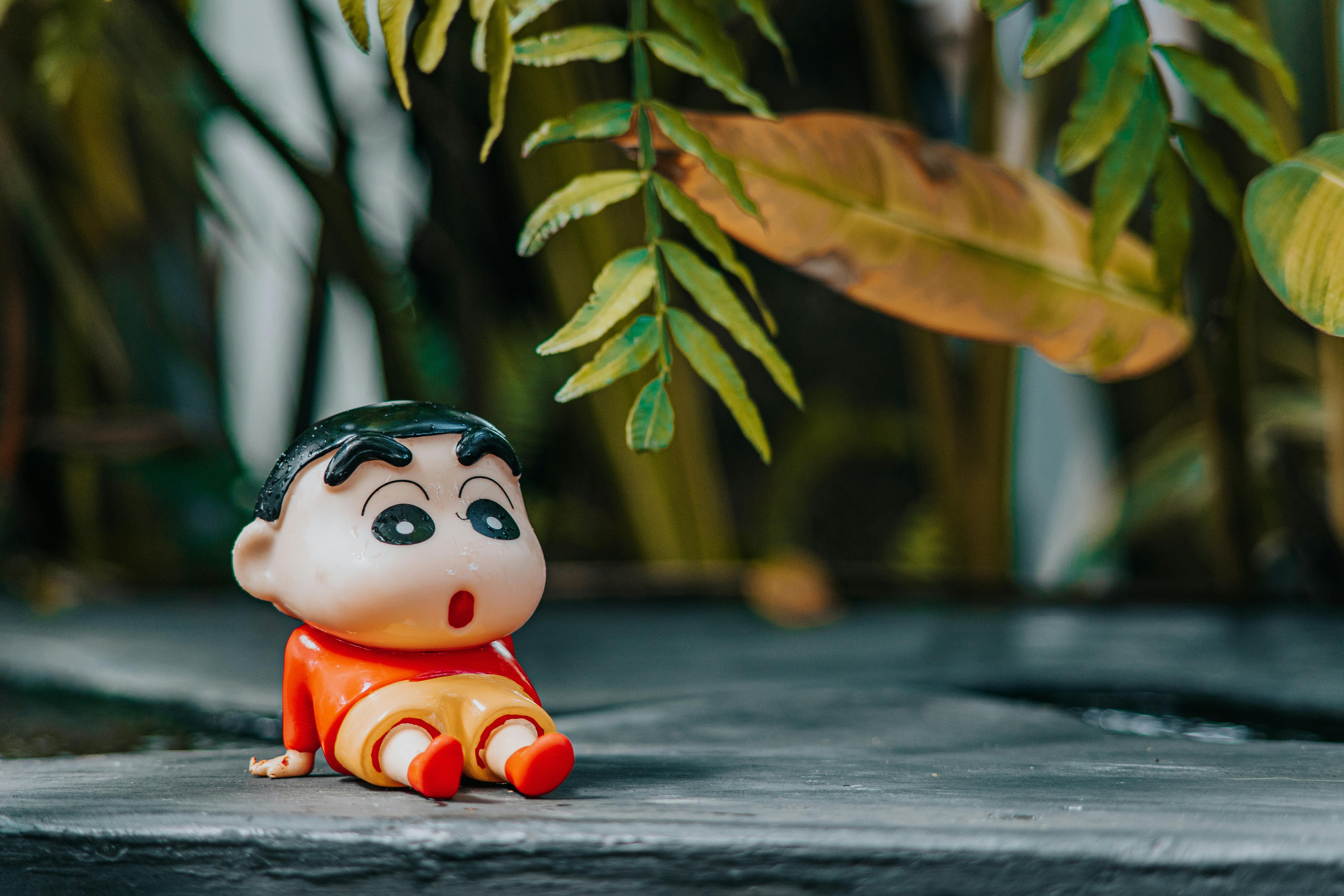 A colorful cartoon character toy positioned outdoors with lush green leaves.