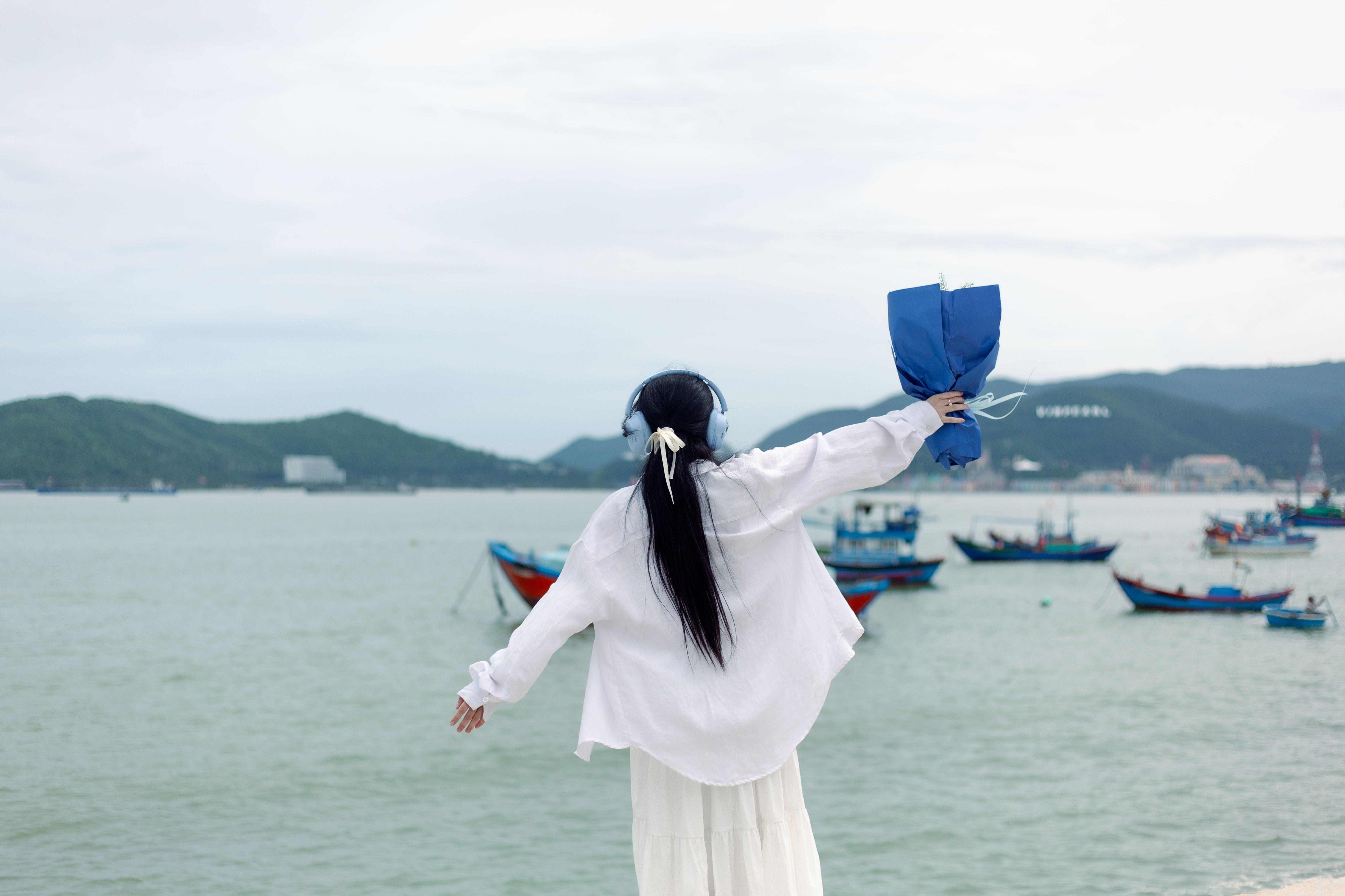 Woman Enjoying Sea Breeze Holding Blue Bouquet · Free Stock Photo