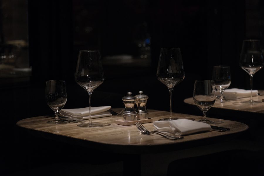 The dining room at Mercer and Vine at night, marble tables set with wine glasses