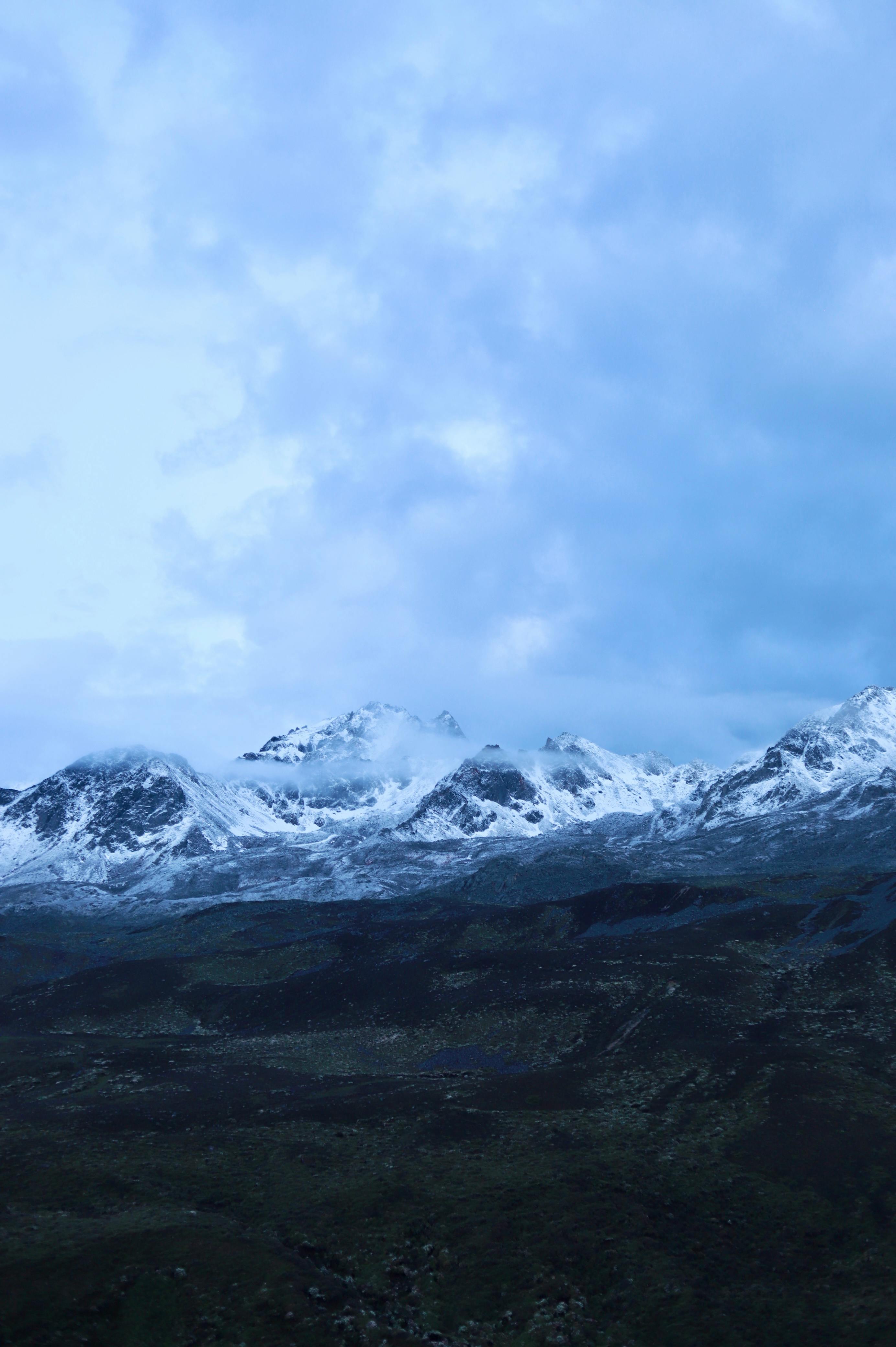 snow capped mountain range under cloudy sky