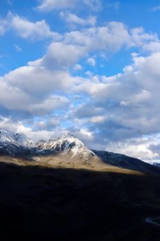 Beautiful sunrise casting light on snow-capped mountains with a dramatic sky in Sichuan, China.