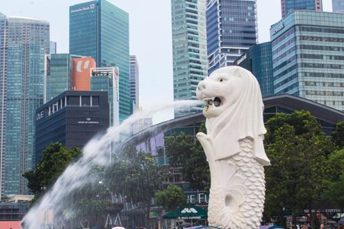 Free The Merlion statue with flowing water in front of Singapore's modern cityscape. Stock Photo