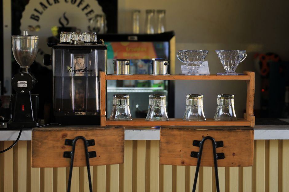 Photo by Jeffry Surianto on Pexels Cozy coffee shop counter with brewing equipment and wooden chairs.