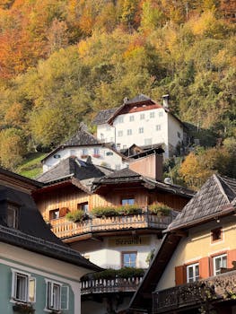 Discover the picturesque architecture of Hallstatt, Austria, nestled against vibrant autumn foliage.