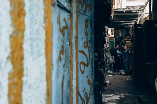 Two men converse in a narrow alleyway in Damietta, Egypt, capturing local street life.