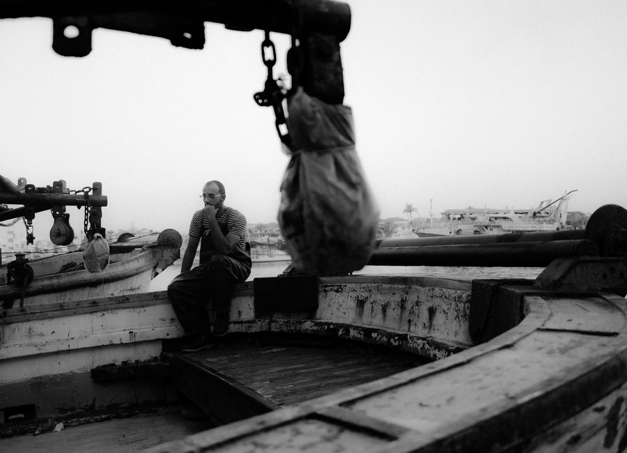 A contemplative scene of a man sitting on a fishing boat in Damietta, Egypt.