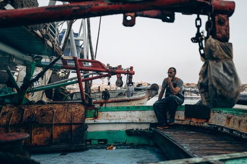 Free A fisherman takes a break on a colorful fishing boat docked at Damietta, Egypt. Stock Photo
