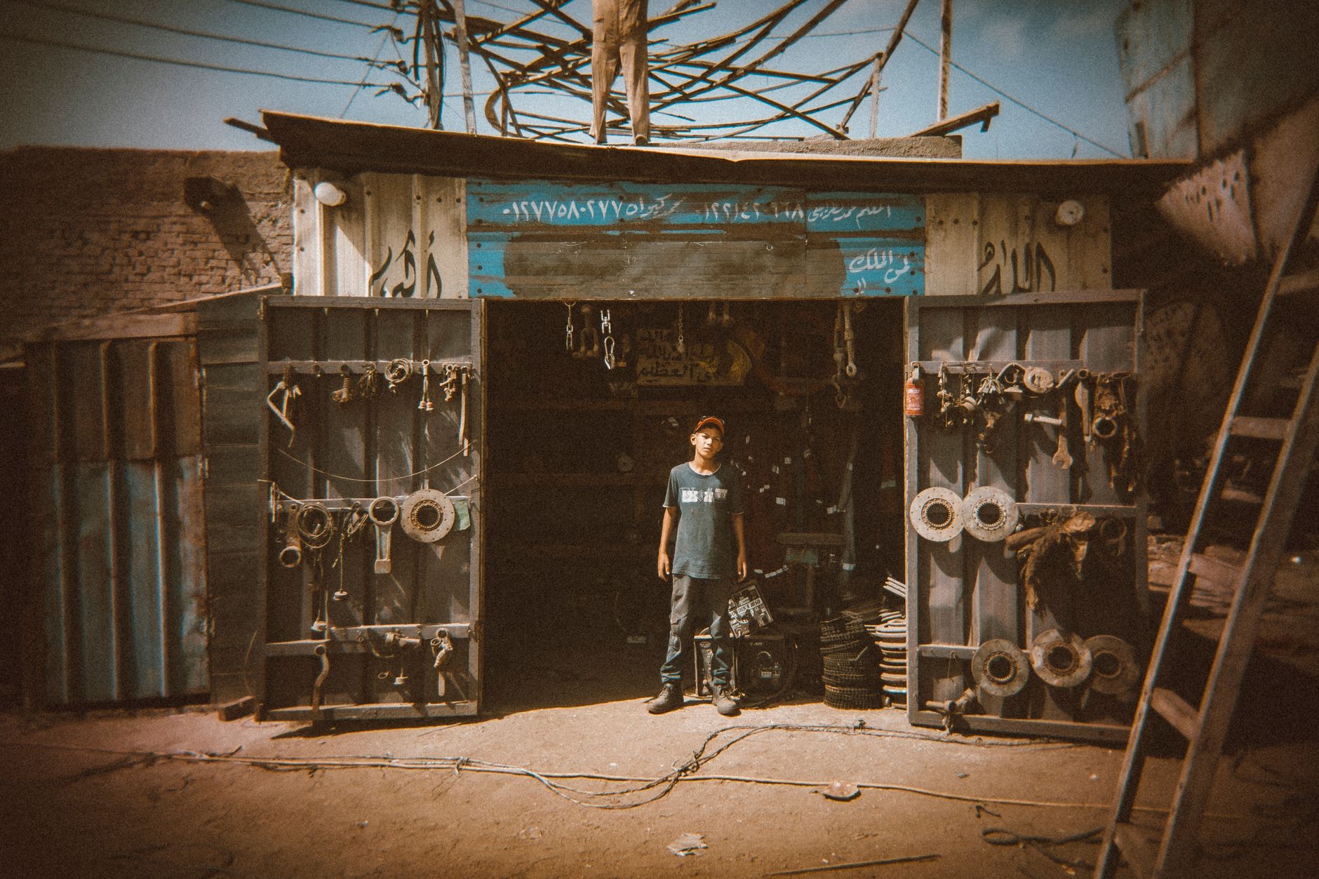 Captivating street photograph of a young man in front of a workshop in Damietta, Egypt.