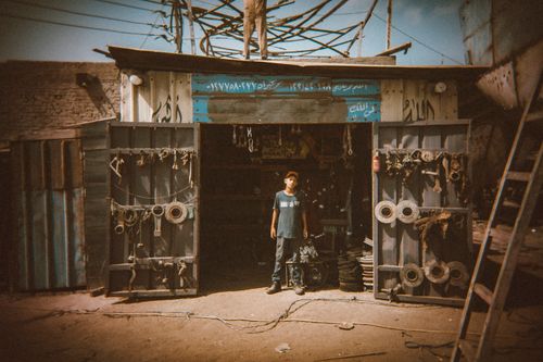 Free Captivating street photograph of a young man in front of a workshop in Damietta, Egypt. Stock Photo