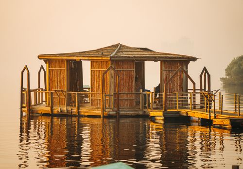 Free A rustic bamboo floating hut reflects on tranquil water, ideal for eco-friendly retreats. Stock Photo
