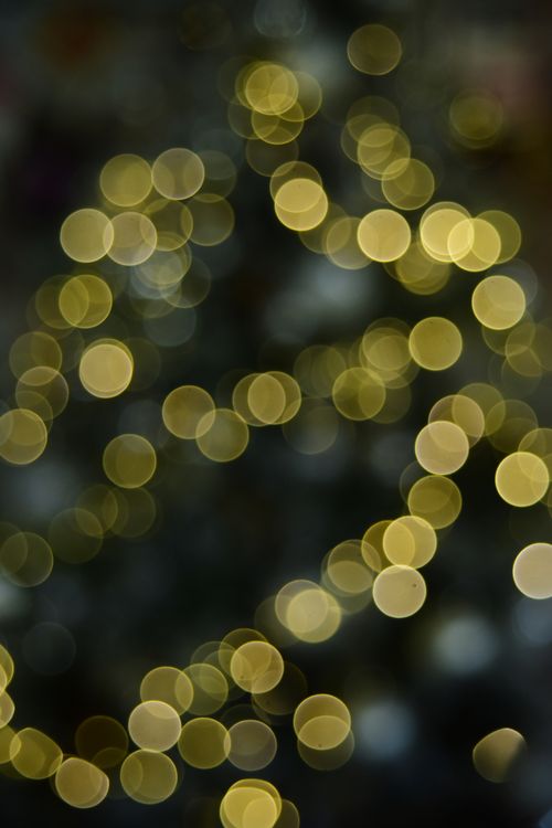 Free A captivating display of soft golden bokeh lights on a dark background creates a dreamy atmosphere. Stock Photo