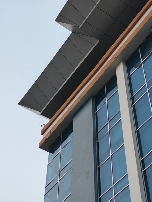 Free Close-up of a modern office building's glass facade with angular roof design. Stock Photo