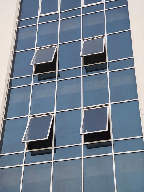 Free Blue glass building facade with open windows creating an abstract architectural pattern. Stock Photo