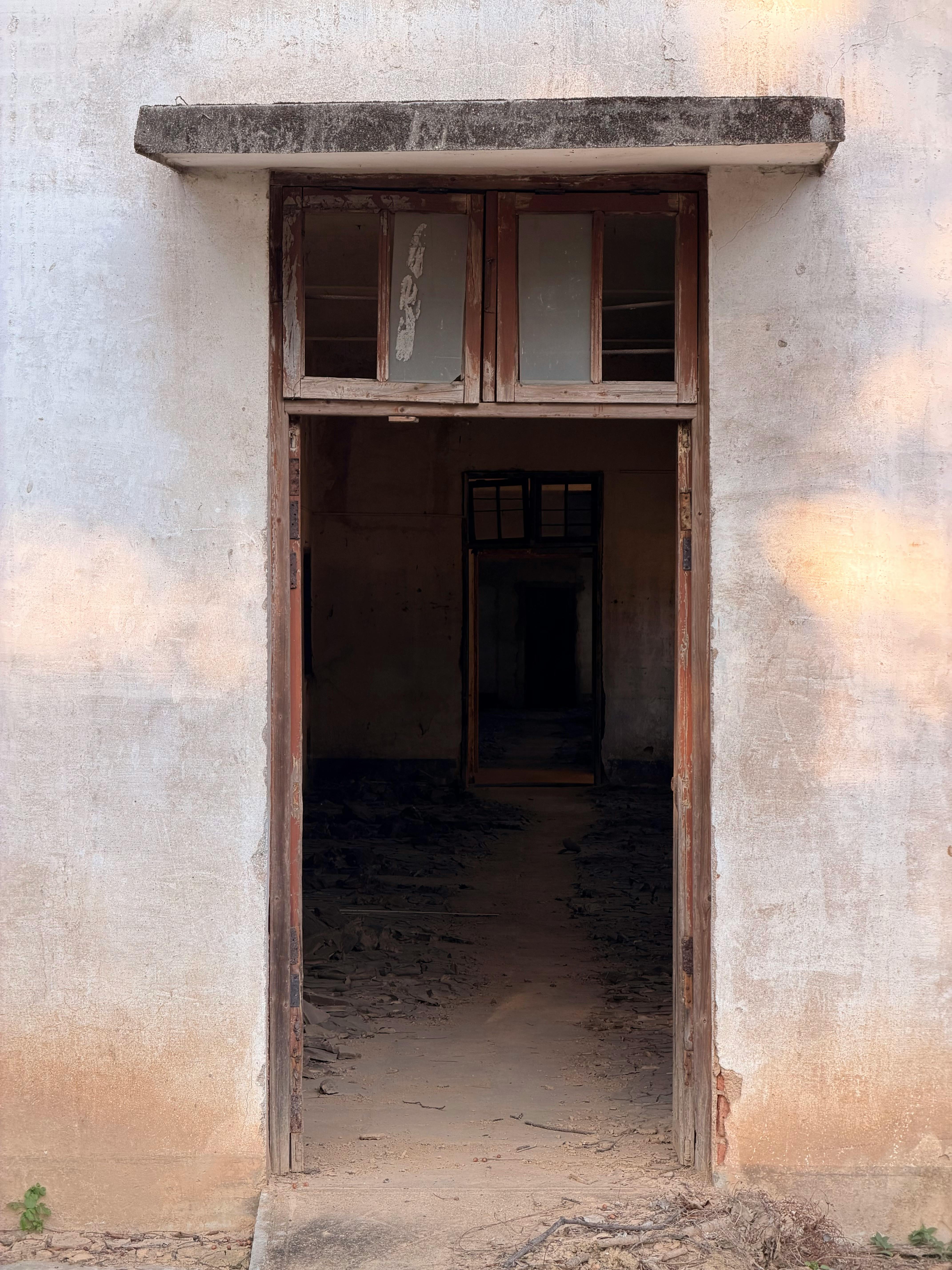 A rustic doorway leads into the depths of an abandoned building, casting mysterious shadows.