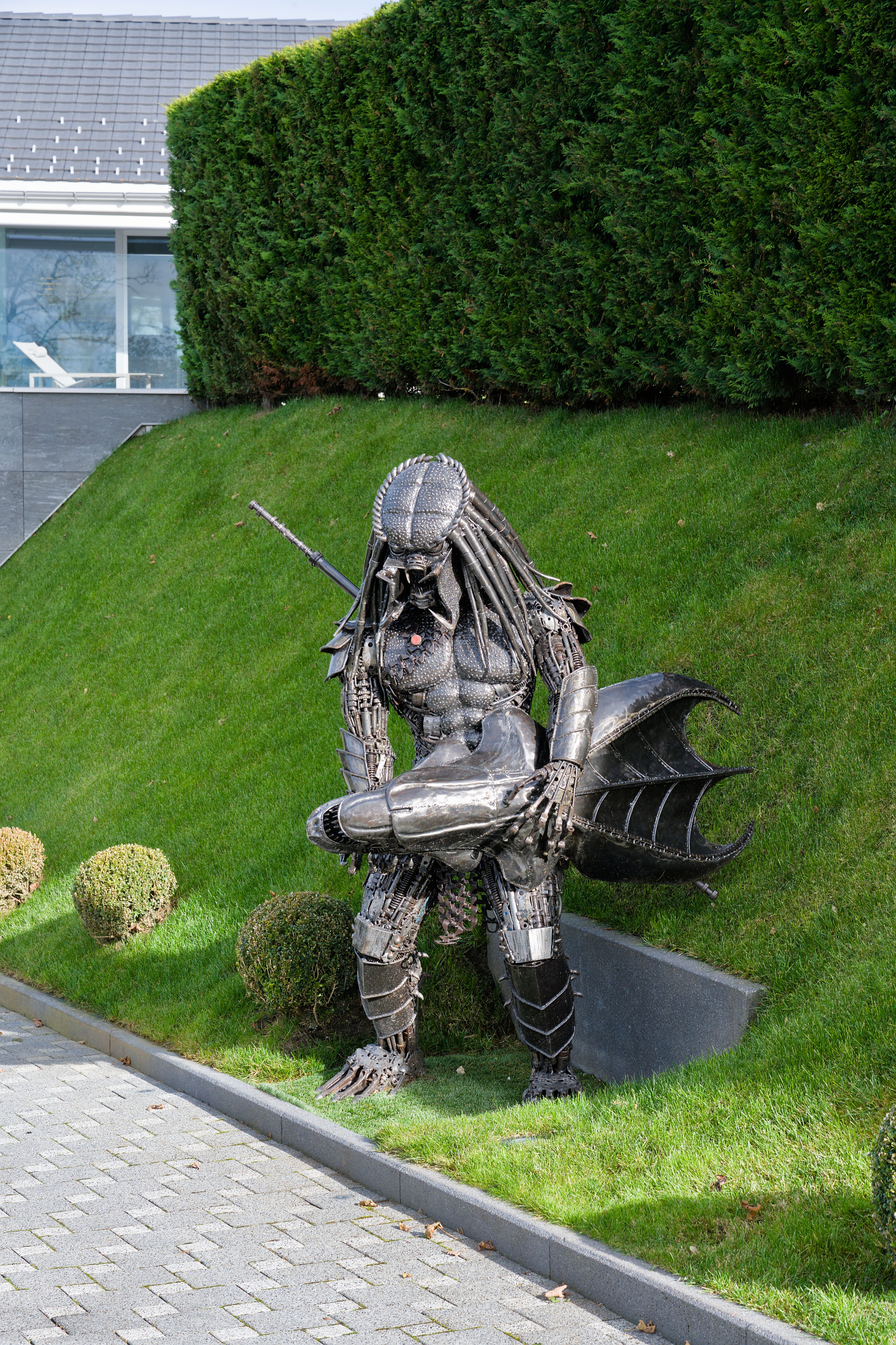 A striking metal Predator sculpture stands in a well-manicured Swiss garden.