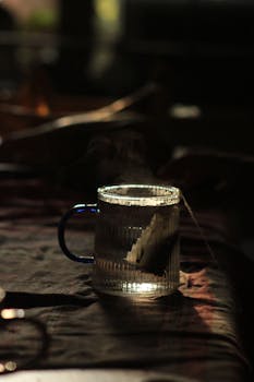 A moody photo of a teacup with a teabag, captured in warm dim lighting.